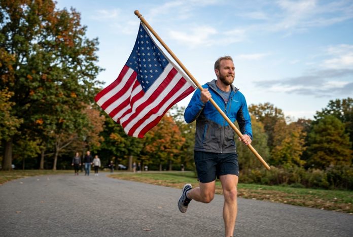 Man running along a park path while waving an American flag on a wooden pole.