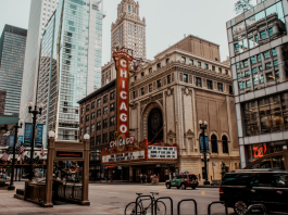 Vertical CHICAGO sign on the Chicago Theatre marquee along a busy downtown street with modern glass buildings nearby. (Informative: identifies the theater and location/context)