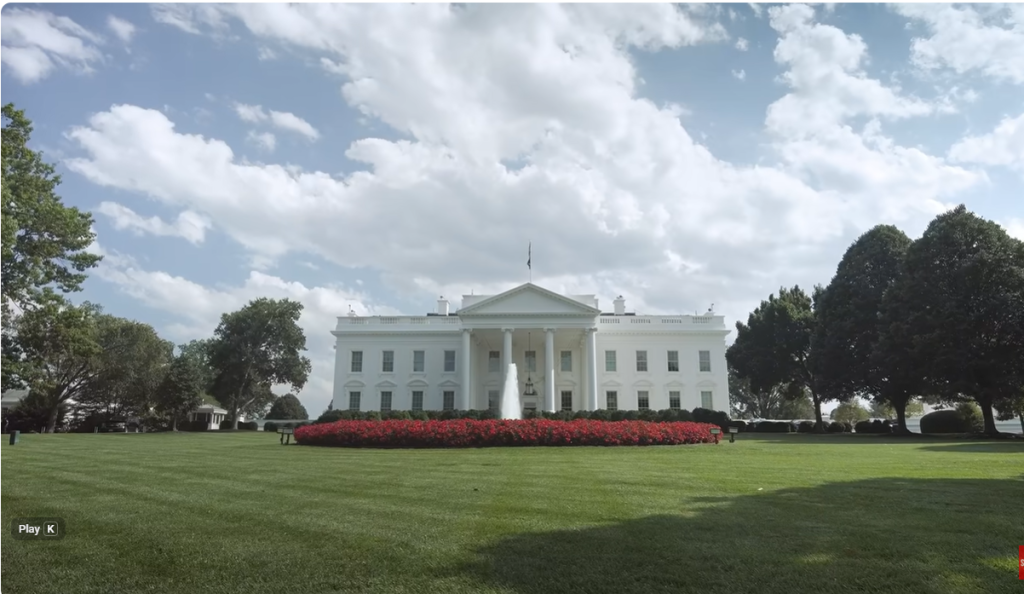 Front View of the White House with a Circular Fountain and a Red Flowering Border on the Lawn, Under a Blue Sky with Clouds. Front View of the White House with a Circular Fountain and a Red Flowering Border on the Lawn, Under a Blue Sky with Clouds. Front View of the White House with a Circular Fountain and a Red Flowering Border on the Lawn, Under a Blue Sky with Clouds. Front View of the White House with a Circular Fountain and a Red Flowering Border on the Lawn, Under a Blue Sky with Clouds.